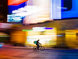 man in green jacket riding bicycle on road during daytime