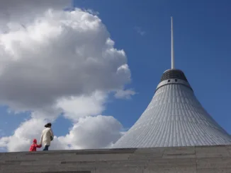 woman and child walking beside gray concrete building